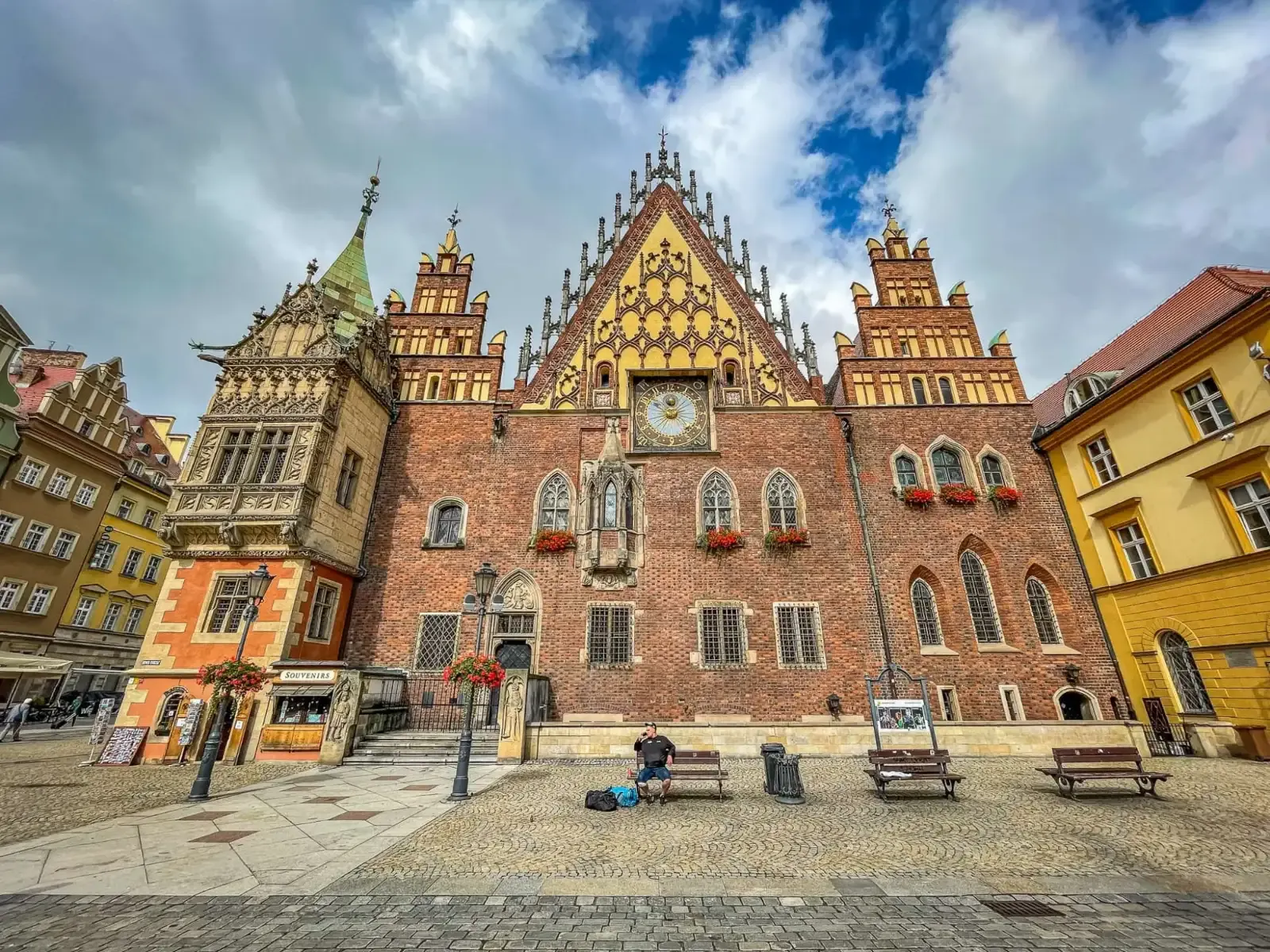Wroclaw Old Town Hall, a large Gothic brick building with ornate gables and a clock tower, seen from the market square.