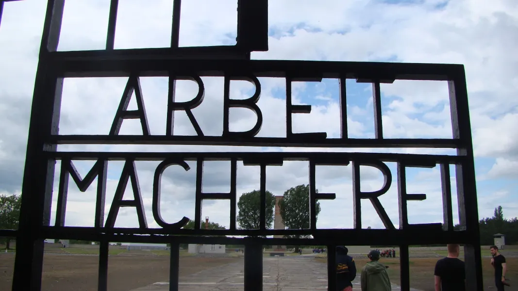 Turyści odwiedzający bramę obozu koncentracyjnego Sachsenhausen w Berlinie, Niemcy.