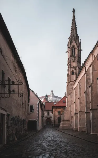 Calle empedrada en el casco antiguo de Bratislava con el Castillo de Bratislava al fondo.
