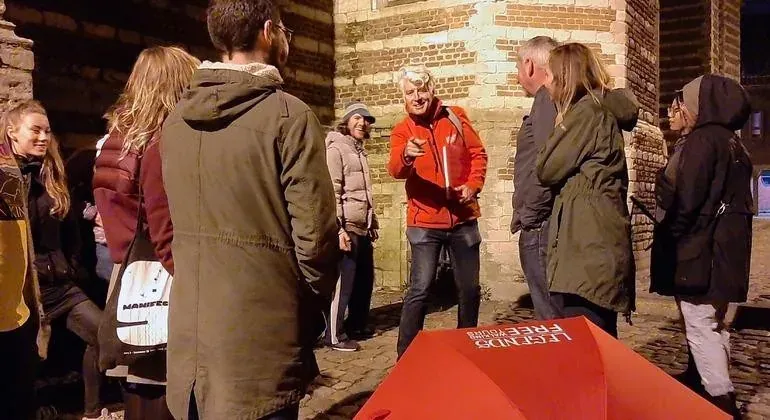 A guided tour group explores Bruges at night.