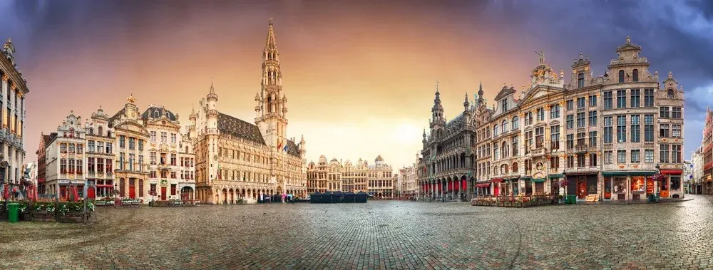 Widok wschodu słońca na Grand Place w Brukseli, prezentujący jego wspaniałą architekturę.