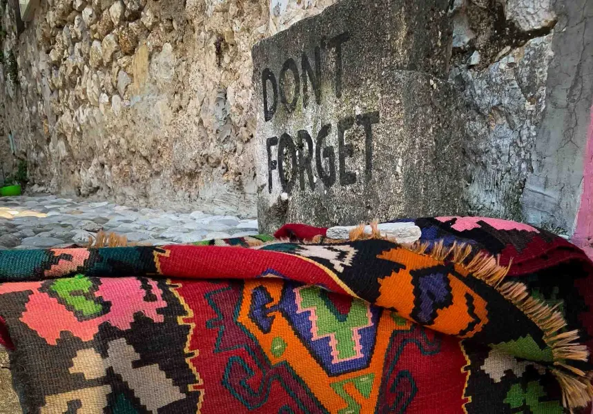 Bunter Teppich in Berat, Albanien, in der Nähe einer Steinmauer.