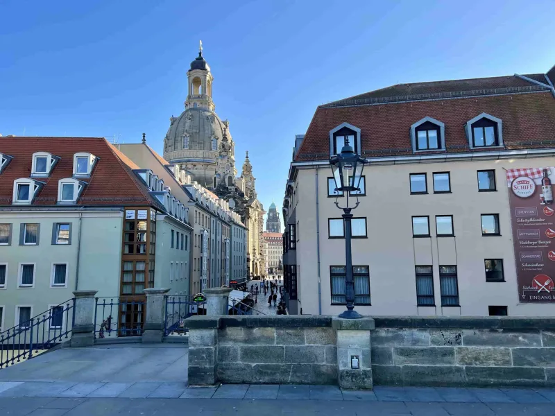 Una encantadora calle en Dresde, Alemania, con la cúpula de la Frauenkirche al fondo.