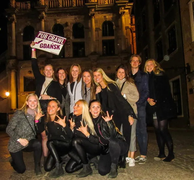 Wesołe turystki i turyści na pub crawl w Gdańsku.