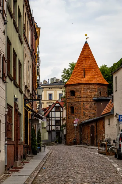 Urocza brukowana ulica w historycznym niemieckim mieście, z ceglaną wieżą.