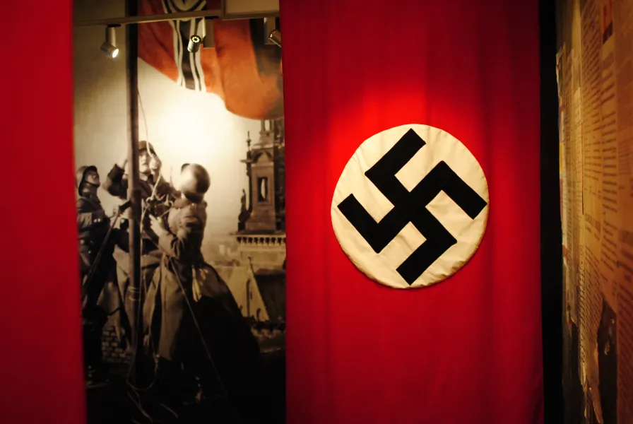 Museum exhibit showcasing a Nazi swastika flag and historical photographs.
