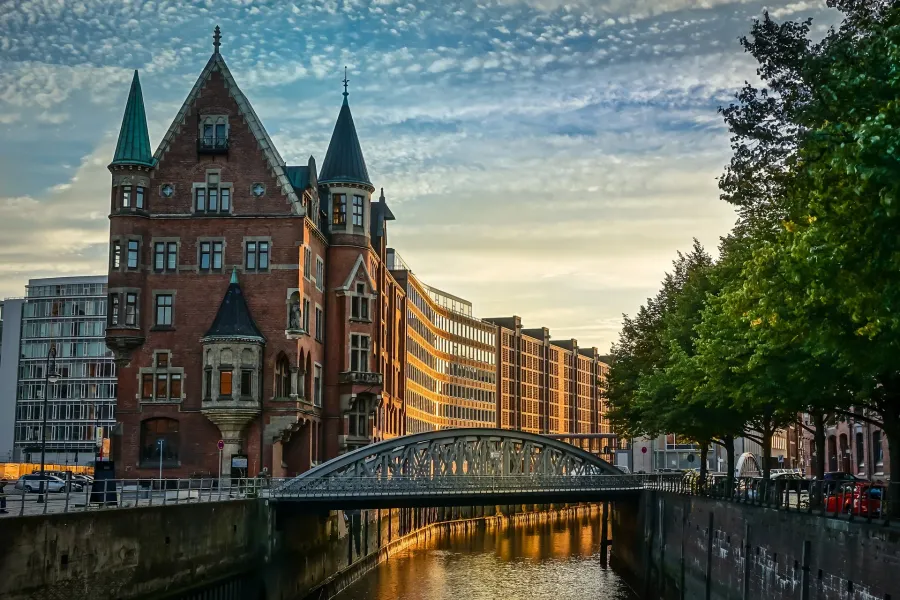 Vista al atardecer de un encantador canal en Hamburgo, Alemania, con un singular edificio de ladrillo y un puente.