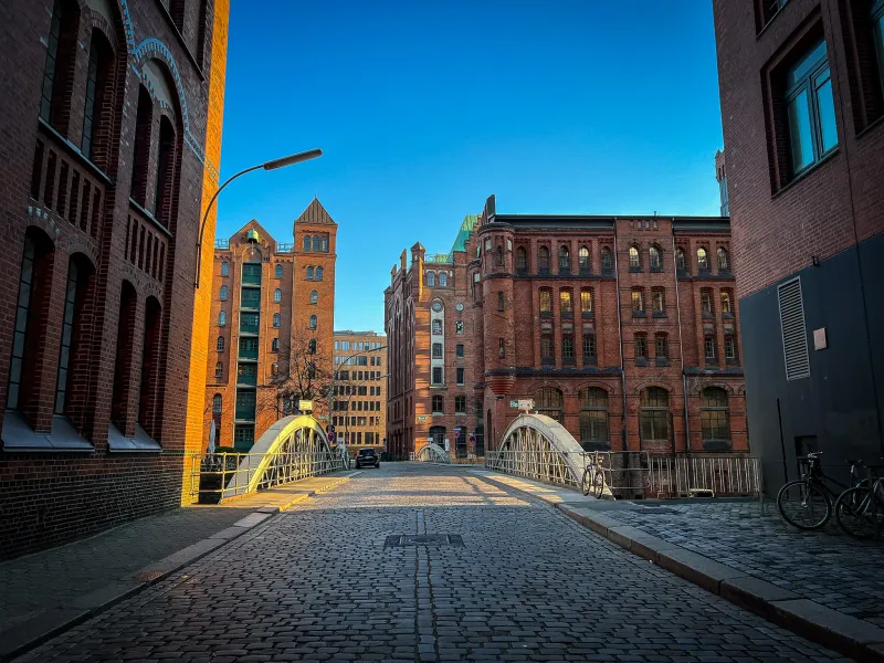 Calle empedrada en Hamburgo, Alemania, que conduce a un puente con edificios históricos de ladrillo.