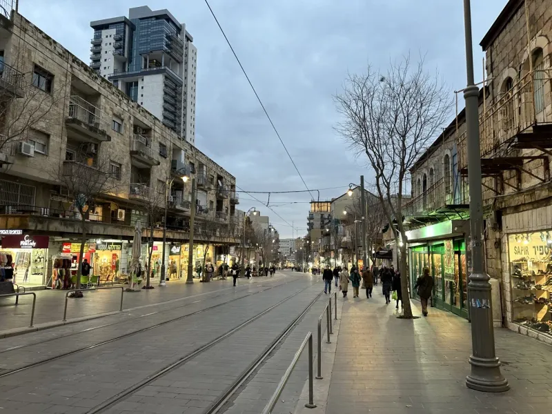 Abendblick auf eine Fußgängerzone in Jerusalem mit Geschäften und Fußgängern.