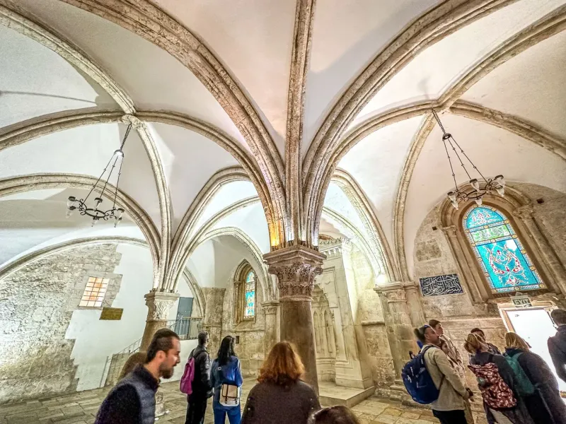 Grupa turystów zwiedzających imponującą architekturę historycznego kościoła w Jerozolimie.