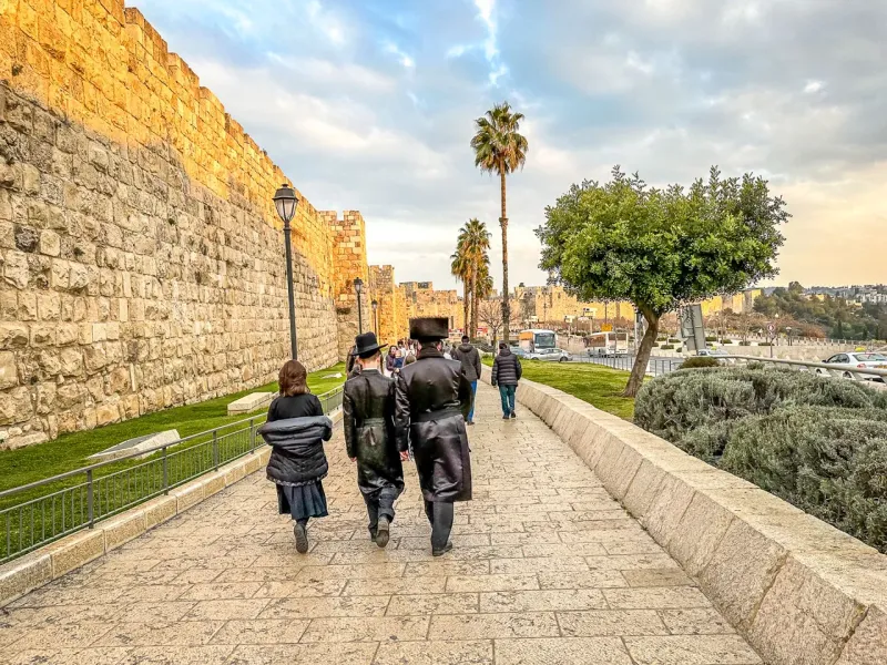 Turistas caminando a lo largo de las antiguas murallas de Jerusalén.