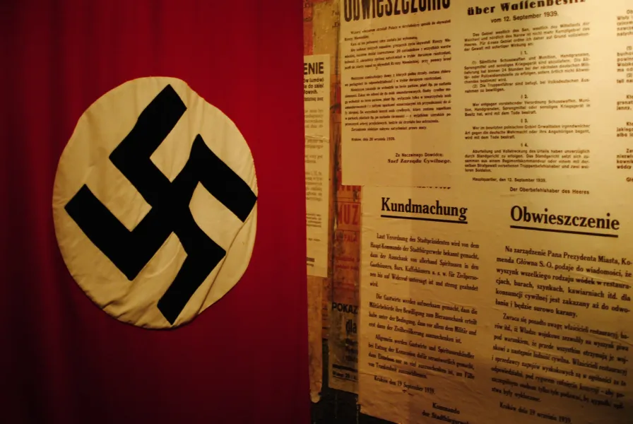 Close-up of a Nazi swastika flag and historical posters in a museum.
