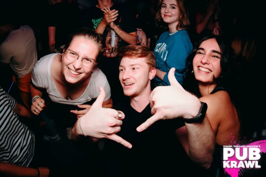 Weseli uczestnicy pub crawl w Krakowie, Polska, cieszą się nocnym życiem.