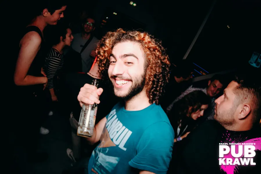 Uśmiechnięty mężczyzna bawi się na pub crawl w Krakowie, Polska.