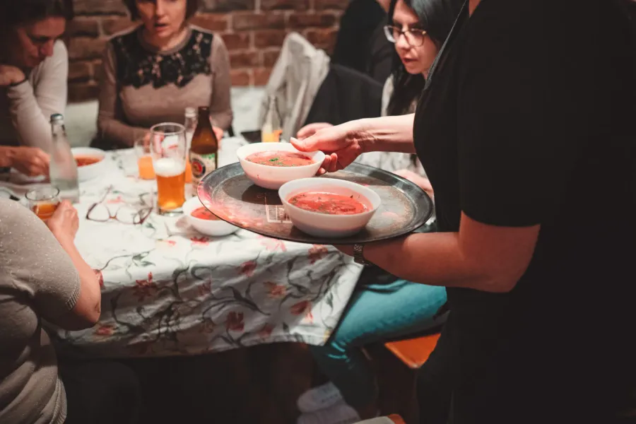 A server brings delicious borscht soup to a group enjoying a food tour in Krakow.