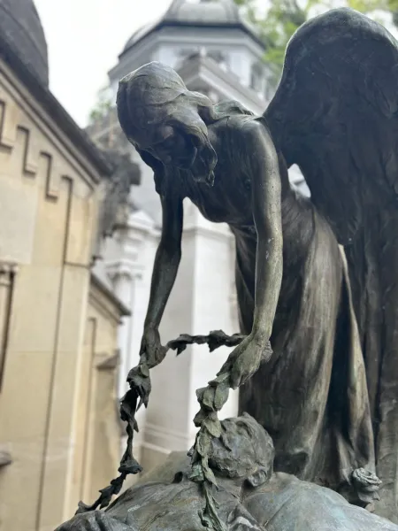 Una escultura de bronce de un ángel en el cementerio Rakowicki de Cracovia, colocando una corona de flores sobre una figura.