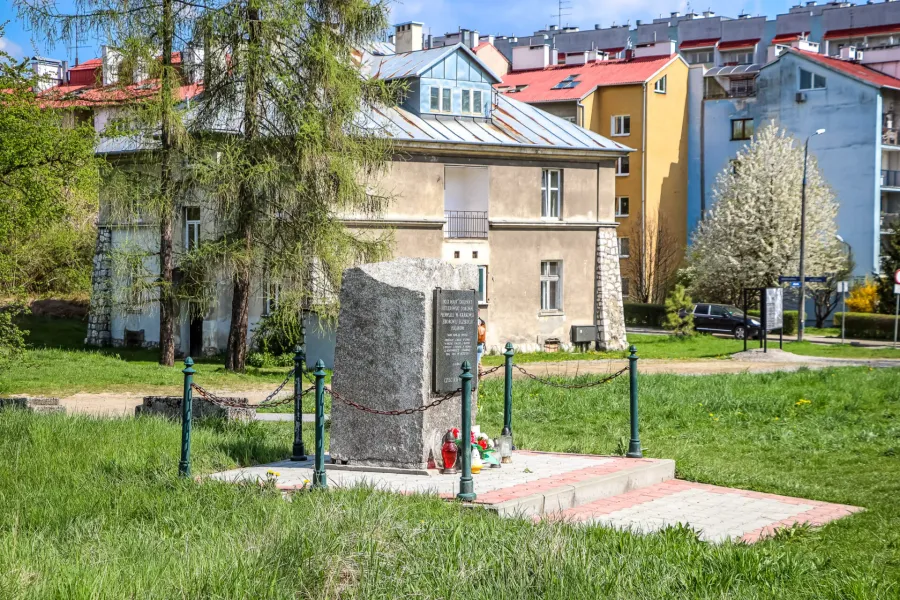 Ein Granitdenkmal in Krakau, Polen, umgeben von Wohngebäuden.