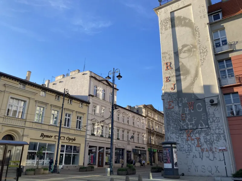 Słoneczna scena uliczna w Krakowie, Polska, z dużym muralem.