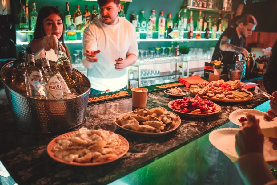 Guests enjoying a Polish food tour in Krakow, sampling pierogi and other local delicacies at a bar.
