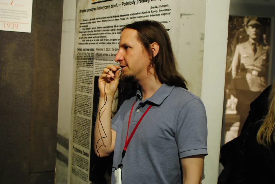 A tour guide leads a group through a Krakow museum, sharing historical insights.