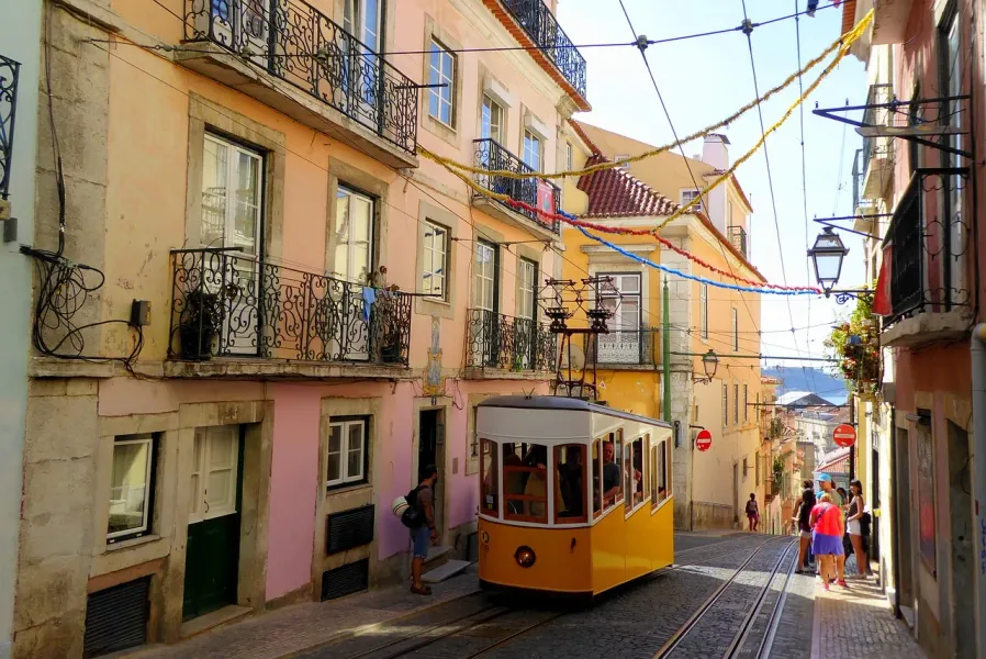 Un tranvía amarillo sube una colina en los distritos de Alfama y Mouraria de Lisboa.