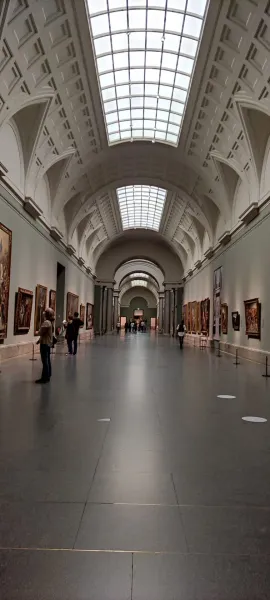 Großer Flur in einem Kunstmuseum mit Gemälden und Besuchern.