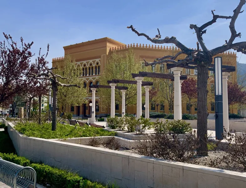 Ruhiger Park in Mostar mit einem schönen gelben Gebäude.