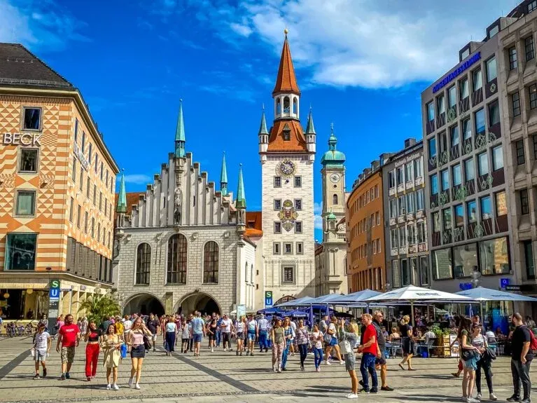Touristen erkunden den Marienplatz in München, Deutschland, mit dem neuen Rathaus im Hintergrund.