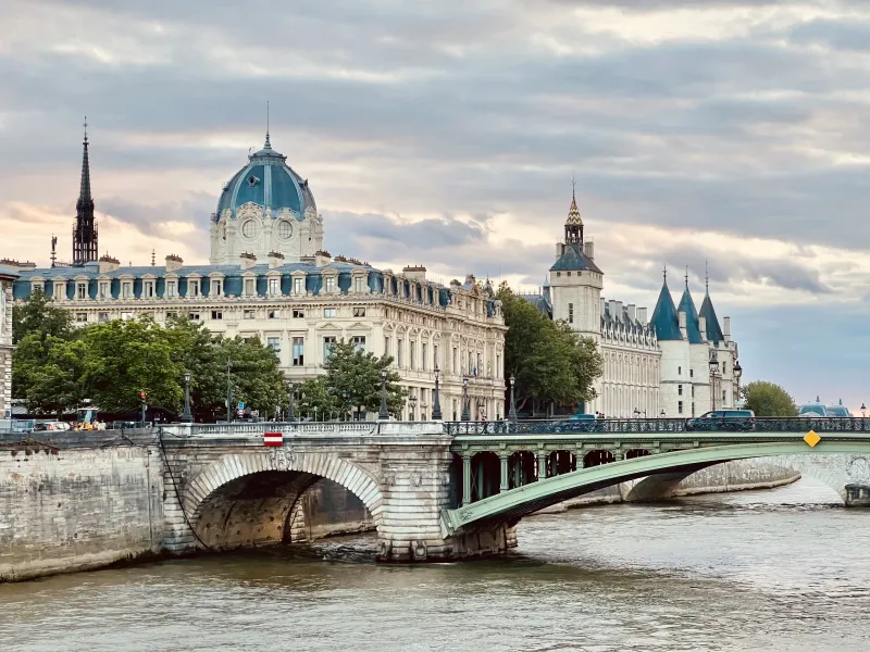 A picturesque bridge in Paris, France, with the Conciergerie and other historical buildings in the background.