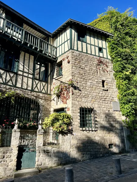 A charming historic building in Paris, showcasing a mix of architectural styles and lush greenery.