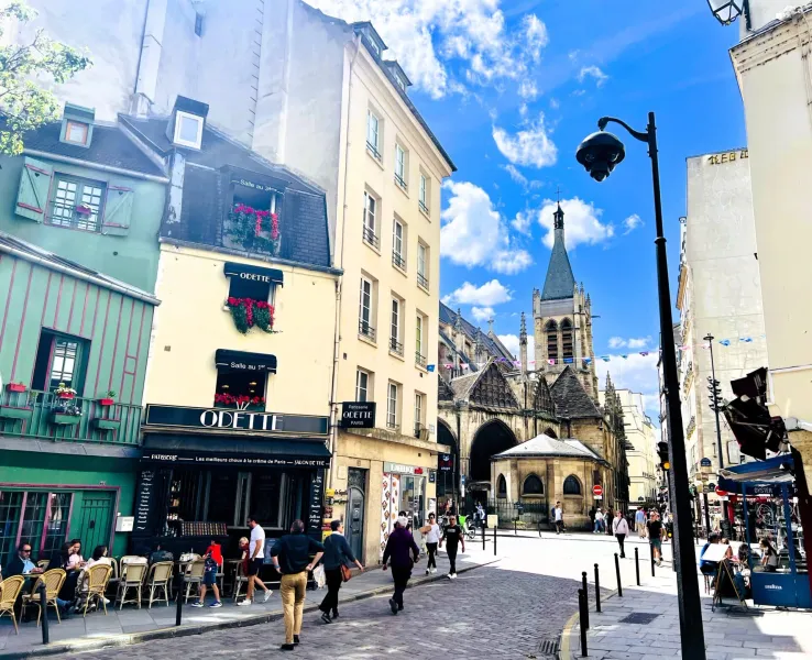 Soleada escena callejera parisina con un encantador café e iglesia histórica.