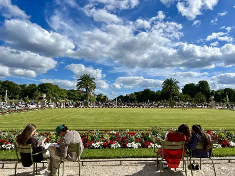 Turistas relajándose en un hermoso jardín parisino.