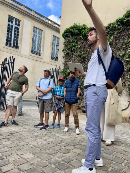 Ein Reiseleiter führt eine Gruppe auf einem Spaziergang durch Paris.