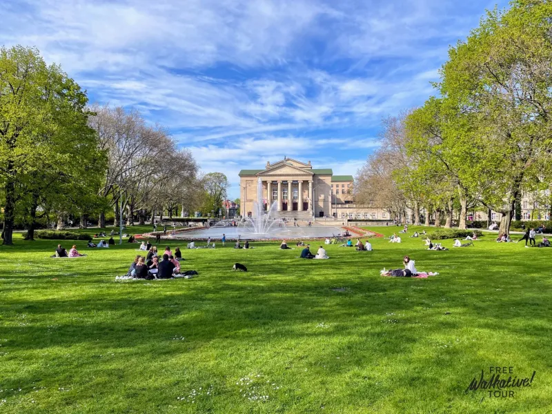 Escena relajante en el parque de Poznań con el Gran Teatro al fondo.