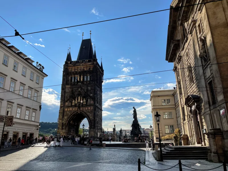 Tourists enjoying the view of the Lesser Town Bridge Tower in Prague.
