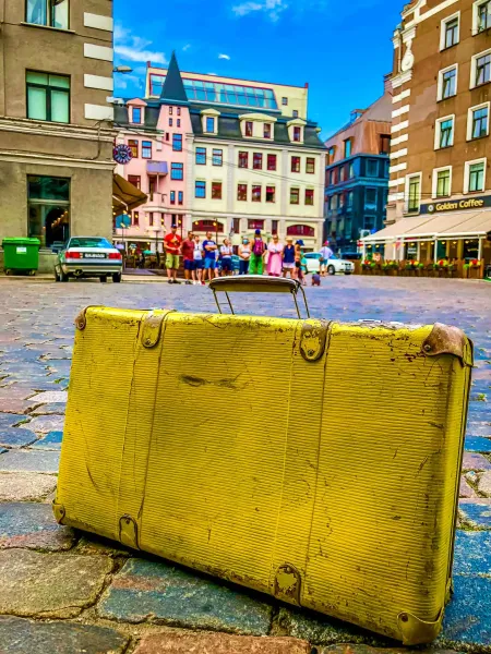 Vintage yellow suitcase on a cobblestone street in Riga, Latvia.