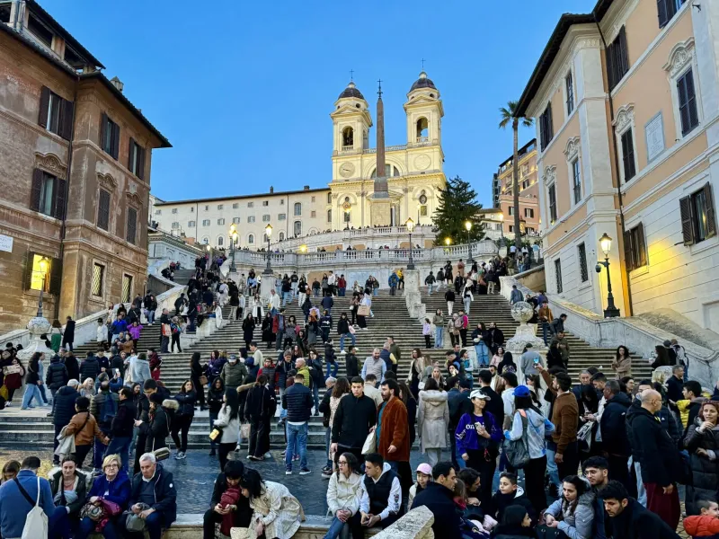 Turistas disfrutando de la Escalinata Española en Roma al atardecer.