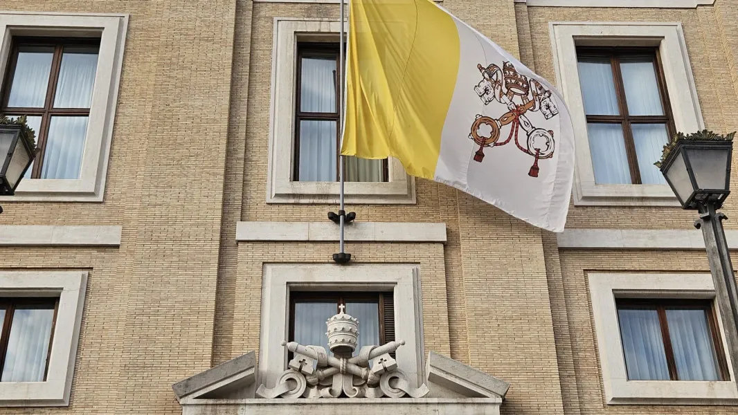 Vatican flag waving outside a building in Rome.