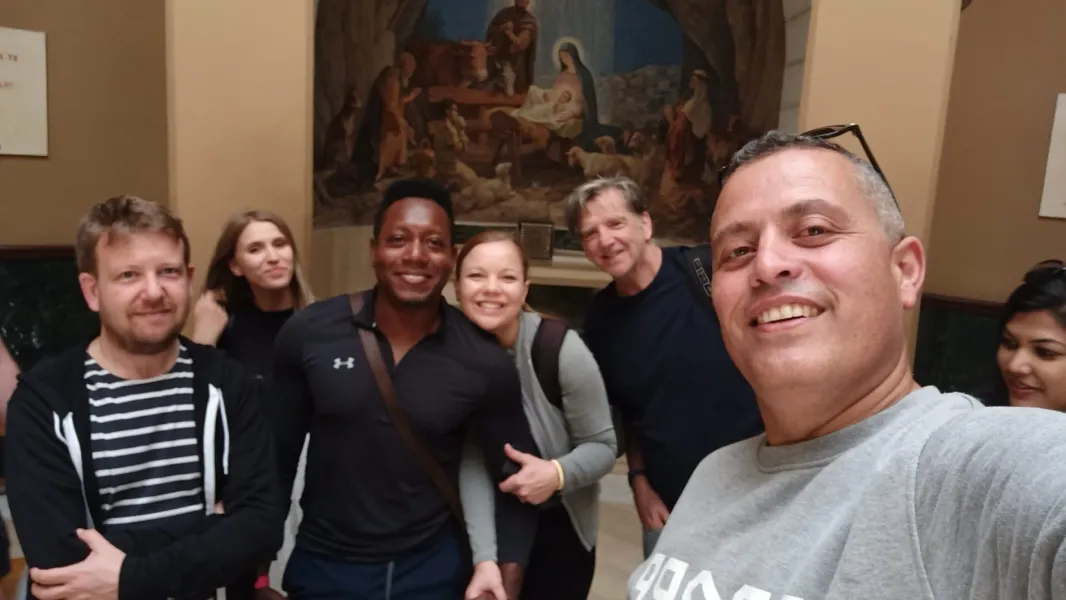 Weseli turyści na wycieczce z przewodnikiem w Rzymie, pozujący do selfie przed obrazem Narodzenia.