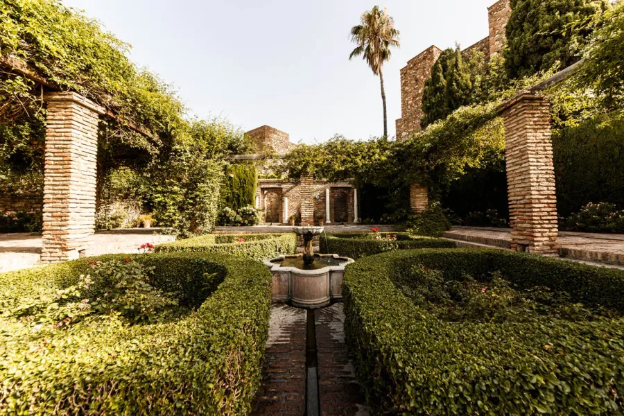 Sereno patio en Sevilla, España, con una fuente y exuberante vegetación.