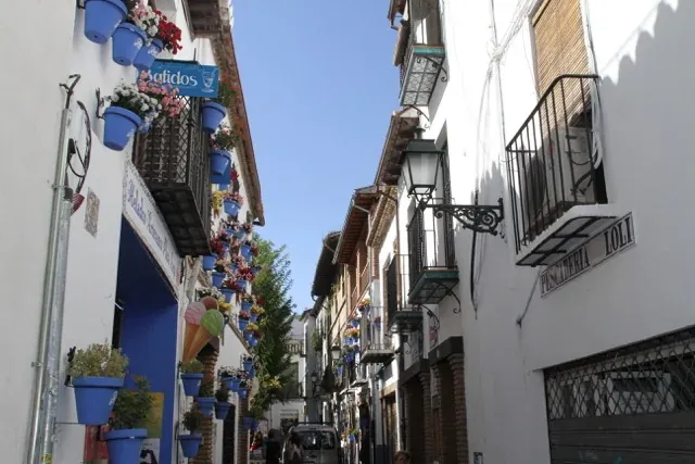 Charming Spanish street with flower-filled pots and traditional architecture.