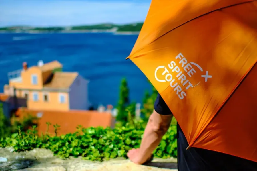 Un guía de Free Spirit Tours con un paraguas naranja, disfrutando de una vista panorámica de Split, Croacia.