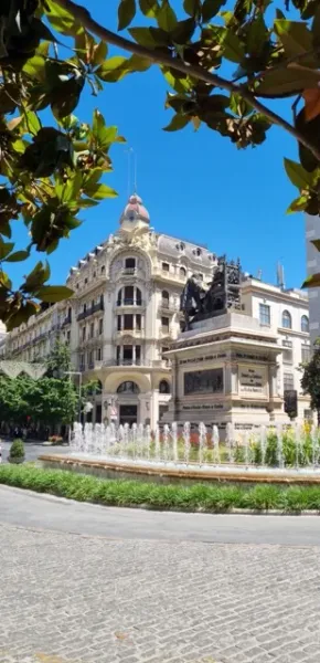 Una hermosa fuente y un edificio ornamentado en una soleada plaza española.