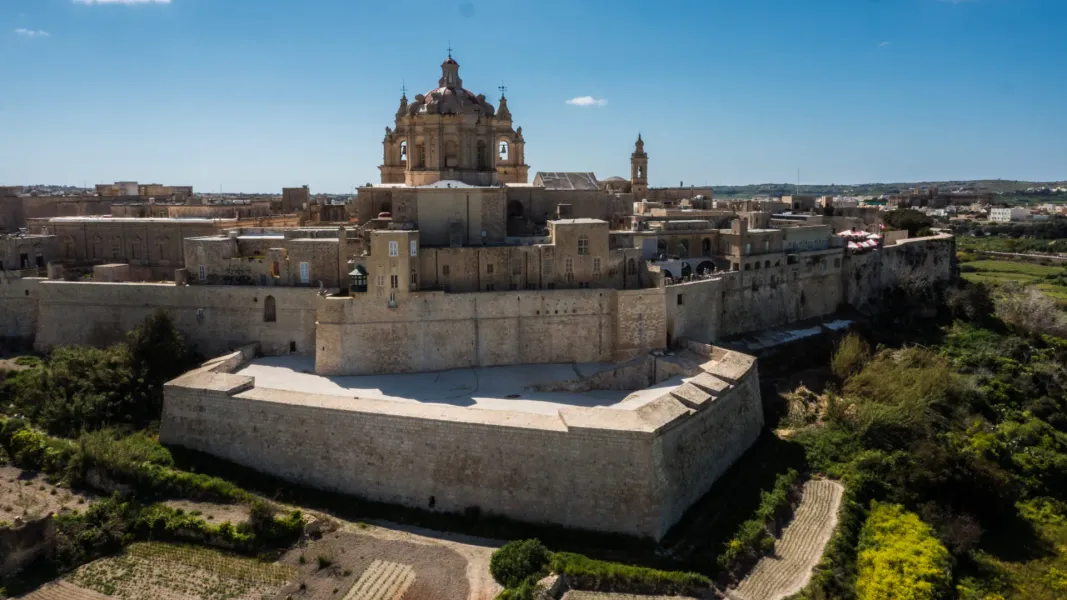 Luftaufnahme einer historischen, befestigten Stadt mit goldenen Steinmauern, Gebäuden und einer großen Kuppelkathedrale un...