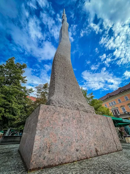Wysoki abstrakcyjny kamienny pomnik we Wrocławiu, Polska, na tle niebieskiego nieba.