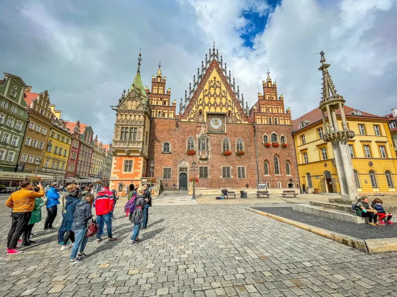 Grupo de turistas admirando el antiguo ayuntamiento en la plaza del mercado de Wrocław.