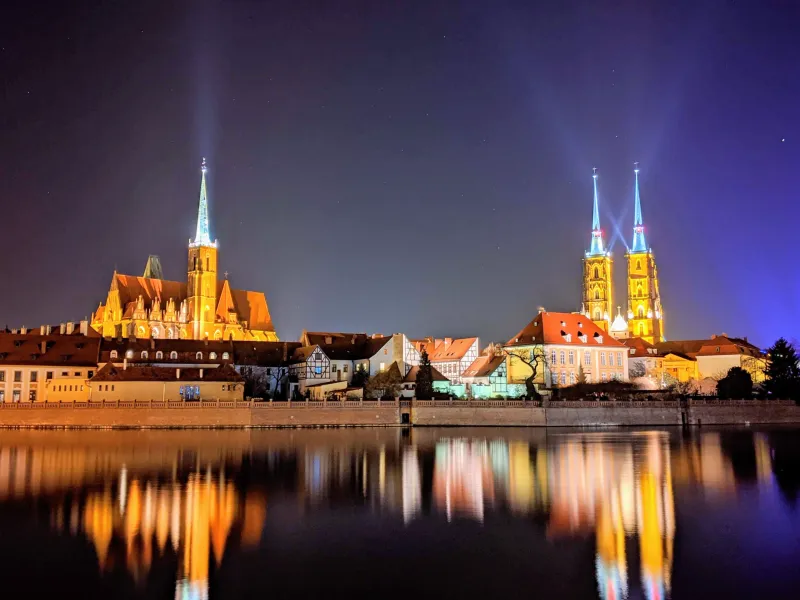 Nachtaufnahme der Kathedrainsel in Wrocław, die sich im Fluss Oder spiegelt.