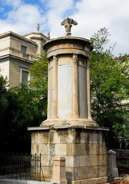 The Choragic Monument of Lysicrates, an ancient monument with Corinthian columns, surrounded by trees and buildings in Ath...