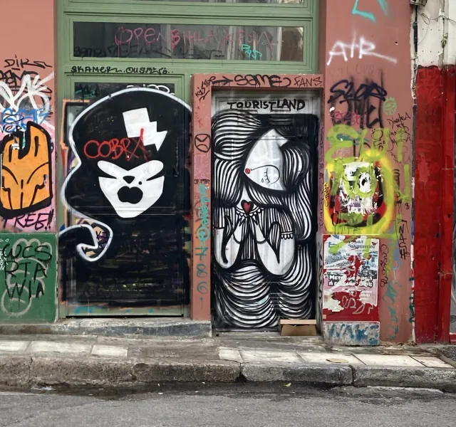 Two urban doors and surrounding walls covered in various street art and graffiti, featuring stylized figures and abstract ...