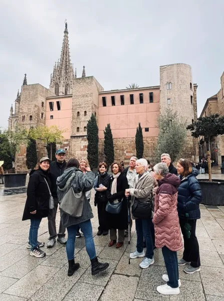 A tour guide speaking to a group of visitors in front of the Cathedral of Barcelona in the Gothic Quarter.